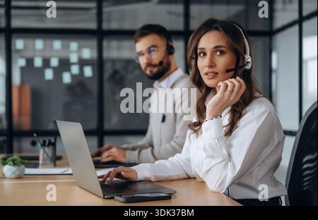 Support-Team für Kopfhörer. Mann und Frau arbeiten im Büro. Stockfoto