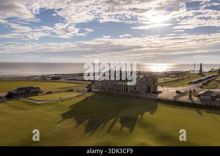 Blick aus der Vogelperspektive auf das Old Course Clubhouse, das lange Schatten auf dem üppig grünen Fairway wirft, mit dem Meer auf den Himmel in einem trüben Horizont, St Andrews, SC Stockfoto