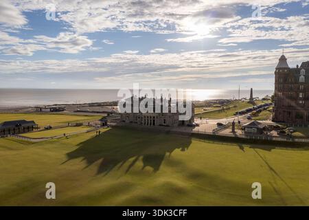 Blick aus der Vogelperspektive auf den berühmten Royal and Ancient Golf Club von St Andrews, der sich im Sonnenlicht sonnt, und sein Schatten erstreckt sich über die üppige grüne Landschaft, St Stockfoto