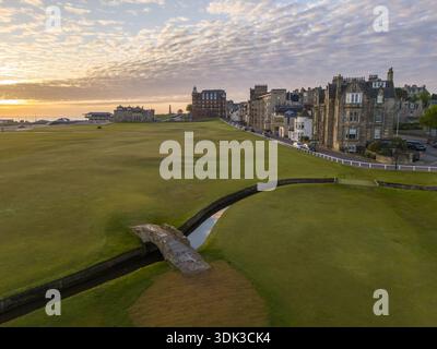 Blick aus der Vogelperspektive auf die berühmte Swilcan Bridge über den Burn auf dem üppigen, grünen Old Course, berührt vom warmen Schein der untergehenden Sonne, St. Andrews, Scotl Stockfoto