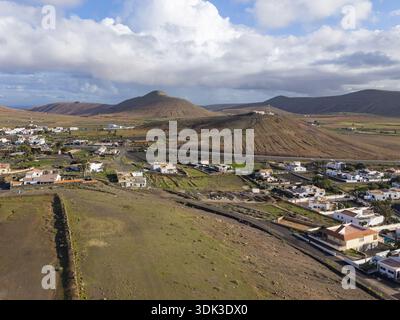 Aus der Vogelperspektive auf die Landschaft mit ländlichen Häusern und vulkanischen Kegeln unter einem bewölkten Himmel, La oliva, Fuerteventura, Spanien. Stockfoto
