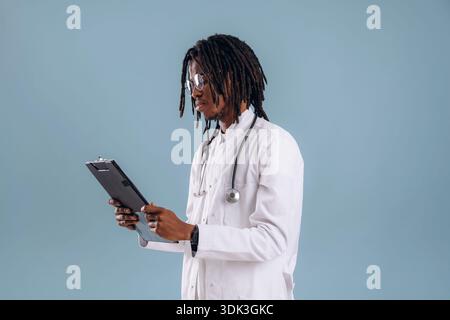Notizblock halten, Doktor. Schwarzer Mann ist im Studio vor weichem Hintergrund. Stockfoto