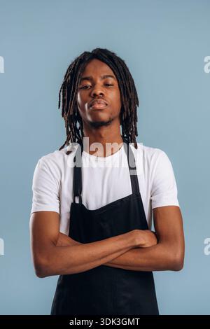 Der Barista steht auf der Schürze. Schwarzer Mann ist im Studio vor weichem Hintergrund. Stockfoto