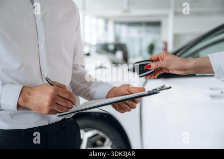Schlüssel für das Auto halten. Nahaufnahme von Mann und Frau ist der Händlerbetrieb. Stockfoto