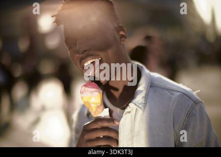 Mann mit Eiskegel mit einem entspannten Ausdruck in der Stadt, Zucker, Industriezucker, süßes Dessert, Desserts, Eis lecken, ungesund Stockfoto
