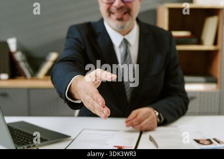 Mann mittleren Alters, der während des Vorstellungsgesprächs die Hand für Handshake ausstreckt Stockfoto