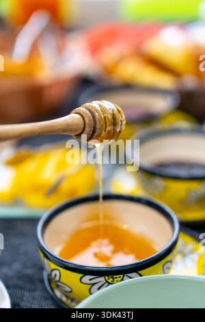 Honig aus einem Holzlöffel in eine Schüssel tropft Stockfoto