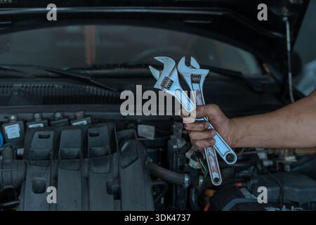 Mechaniker, der Schraubenschlüssel hält, während er in einer Werkstatt an einem Automotor arbeitet Stockfoto