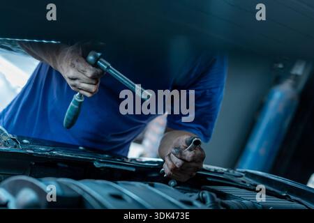 Mechaniker, der den Motor des Fahrzeugs mit einem Schraubenschlüssel repariert Stockfoto