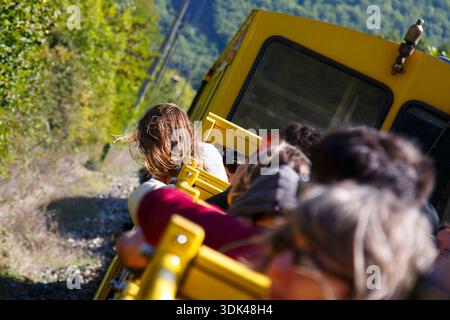 Offener Wagen des gelben Zuges „Le Train jaune“, der bergauf fährt, Ligne de Cerdagne, Vallée de la Têt, Villefranche-de-Conflent, Pyrénées-Oriental Stockfoto