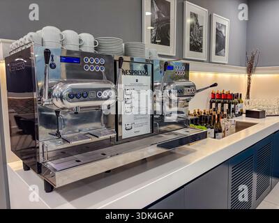 Professionelle Nespresso Kaffeemaschine/Barista Station. Espresso, stapelbare Tassen und Weinauswahl in der modernen Flughafenlounge. Stockfoto