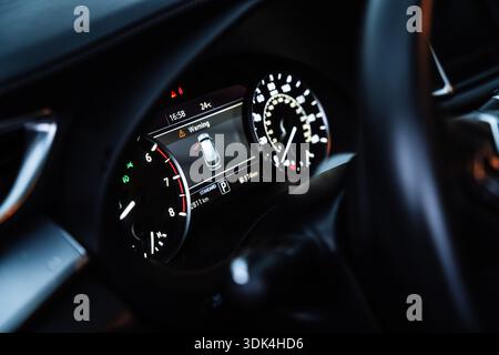 Nahaufnahme eines modernen Innenraums mit beleuchtetem digitalem Kombiinstrument und Bedienelementen auf dem Armaturenbrett. Vorstellung des Konzepts der Fahrzeugtechnik Stockfoto