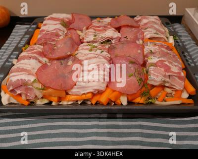 Zubereiteter Fisch und Lachs in Speck auf Karotten und Fenchel mit Dill auf Backblech gewickelt. Ofenform. Kopierraum. Stockfoto