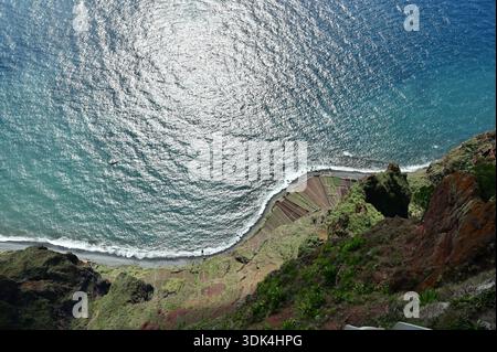 Atemberaubender Blick auf die Klippe von Cabo Girão, Terrassenfelder und den Atlantischen Ozean, Madeira, Portugal. Helle Sonnenreflexion auf blauer Wasseroberfläche Stockfoto