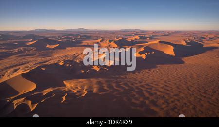 Luftbild von goldenen Sanddünen in der Namib-Wüste während des Sonnenaufgangs, fotografiert aus einem Helikopter in Namibia. Stockfoto