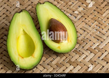 Stillleben mit geschnittenen Avocados im Korbsieb Stockfoto