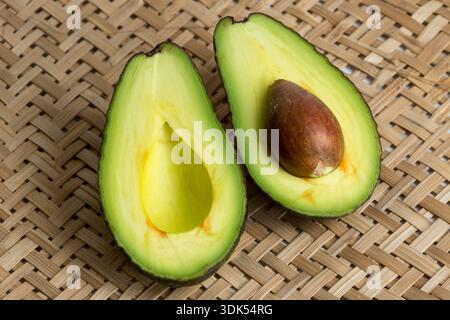 Stillleben mit geschnittenen Avocados im Korbsieb Stockfoto