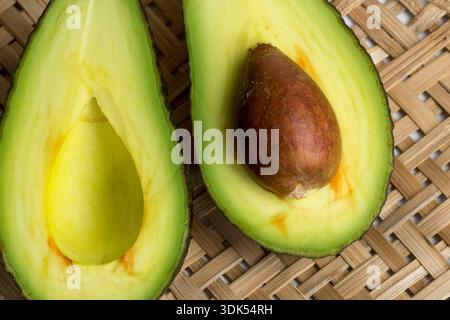 Stillleben mit geschnittenen Avocados im Korbsieb Stockfoto