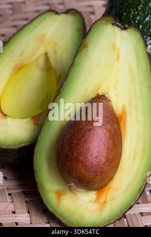 Stillleben mit geschnittenen Avocados im Korbsieb Stockfoto