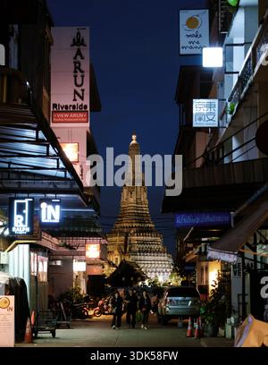 Bangkok, Thailand, 19. November 2025, lebhafte Straßen von Bangkok in der Abenddämmerung, beleuchtet von bunten Schildern und der atemberaubenden Silhouette von Wat Arun. Stockfoto