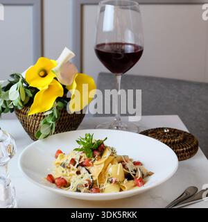Herzhafte Pilznudeln mit Rotwein und Blumendekorationen Stockfoto