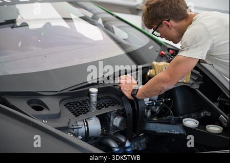 Nahaufnahme einer mechanischen Flüssigkeit (wahrscheinlich Öl oder Kühlmittel) in den Motorraum eines schwarzen Lamborghini Huracán Super Trofeo EVO 2 -Rennwagens in der Boxengasse Stockfoto