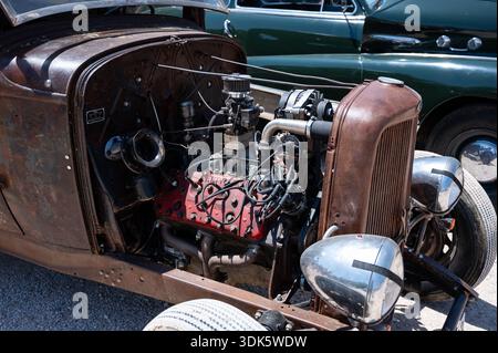 Eine detaillierte Nahaufnahme eines rostigen, modifizierten Ford V8-Flathead-Motors in einem 1932 Rat Rod, der seine rohe und kraftvolle Mechanik zeigt. Stockfoto