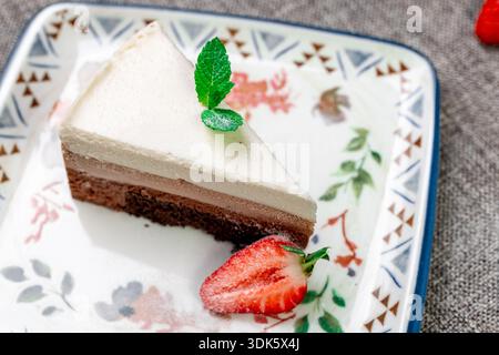 Exquisites, helles und luftiges mehrlagiges Dessert mit „drei Pralinen“ auf einem weißen Teller. Eine vertikale Nahaufnahme zeigt die zarte Textur Stockfoto
