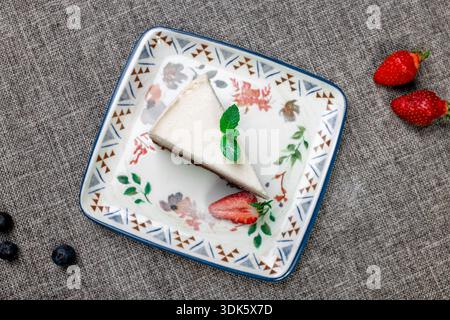 Exquisites, helles und luftiges mehrlagiges Dessert mit „drei Pralinen“ auf einem weißen Teller. Eine vertikale Nahaufnahme zeigt die zarte Textur Stockfoto