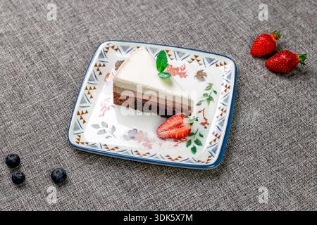 Exquisites, helles und luftiges mehrlagiges Dessert mit „drei Pralinen“ auf einem weißen Teller. Eine vertikale Nahaufnahme zeigt die zarte Textur Stockfoto