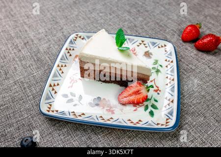 Exquisites, helles und luftiges mehrschichtiges Dessert mit „drei Pralinen“ auf einem weißen Teller. Eine vertikale Nahaufnahme zeigt die zarte Textur von Dunkelheit, Stockfoto