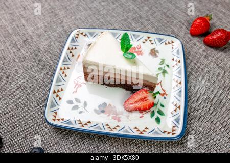 Exquisites, helles und luftiges mehrlagiges Dessert mit „drei Pralinen“ auf einem weißen Teller. Eine vertikale Nahaufnahme zeigt die zarte Textur Stockfoto