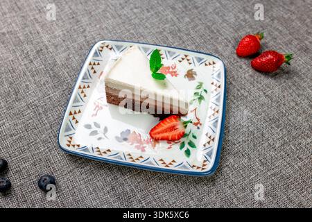 Exquisites, helles und luftiges mehrlagiges Dessert mit „drei Pralinen“ auf einem weißen Teller. Eine vertikale Nahaufnahme zeigt die zarte Textur Stockfoto