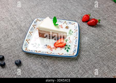 Exquisites, helles und luftiges mehrlagiges Dessert mit „drei Pralinen“ auf einem weißen Teller. Eine vertikale Nahaufnahme zeigt die zarte Textur Stockfoto