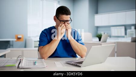 Erschöpfter Latino-Arzt Gestresst Über Internet-Diagnose Im Krankenhausumfeld. Stockfoto