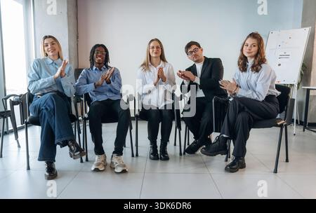 Sitzen und applaudieren. Gruppen junger Geschäftsleute sind im Konferenzraum. Stockfoto