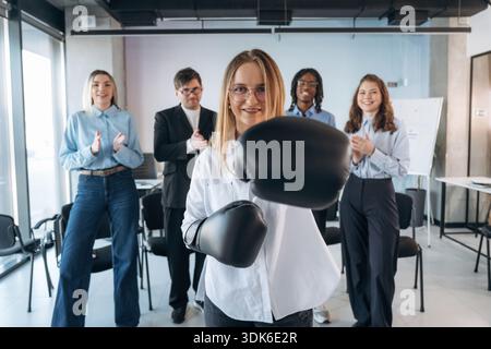 Die Frau trägt Boxhandschuhe. Gruppen junger Geschäftsleute sind im Konferenzraum. Stockfoto