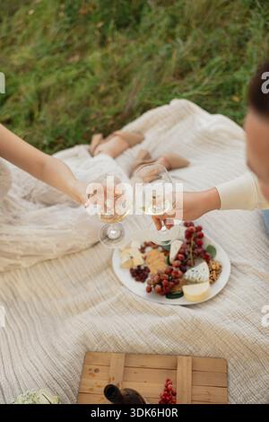 Ein paar toasten Wein bei einem Picknick im Freien Stockfoto