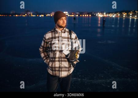 Stehen und weit weg schauen. Ein Mann ist im Winter mit seinen Schlittschuhen auf dem Eis. Stockfoto