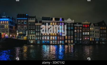 Berühmte Tanzhäuser von Amsterdam bei Nacht mit bunten Lichtern, die sich im Kanal spiegeln, Niederlande Stockfoto