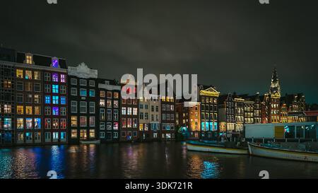 Berühmte Tanzhäuser von Amsterdam bei Nacht mit bunten Lichtern, die sich im Kanal spiegeln, Niederlande Stockfoto