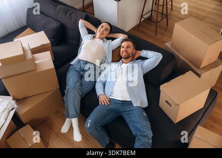 Wellness, auf dem Sofa liegen. Glückliches Paar zog in ein neues Haus. Stockfoto