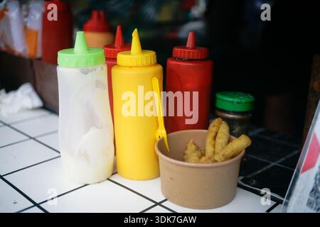 Kartoffeln Pommes Frites in einer braunen Papierschale mit vielen Varianten Flaschensoße Stockfoto