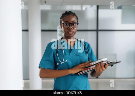 Vorderansicht, stehend. Weibliche Ärztin ist drinnen in einem modernen Zimmer. Stockfoto