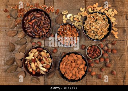 Schüsseln mit verschiedenen Nüssen, Kastanien, Mandeln und Haselnüssen auf einem rustikalen Holztisch. Draufsicht. Stockfoto