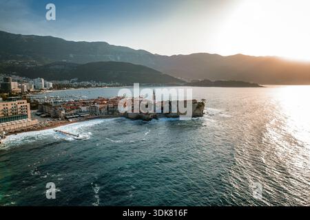 Blick aus der Vogelperspektive auf die Terrakotta-Dächer, die sich hinabstürzen und auf das türkisfarbene Wasser rund um die alte Insel und die Sveti Stefan, Budva, Budva Munici treffen Stockfoto