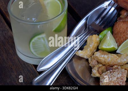 Caipirinha, das berühmte brasilianische Getränk, mit Beilagen der Feijoada, traditionelles Gericht der brasilianischen Küche Stockfoto