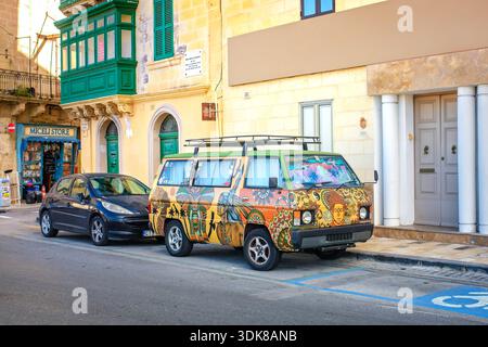 Valletta, Malta - 5. November 2025: Ein Mitsubishi L300 Art Car mit lebendigen ethnischen Wandmalereien mit Buddha und menschlichen Porträts Stockfoto
