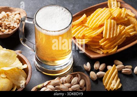 Lager-Bier und Snacks am Steintisch. Muttern, chips Stockfoto