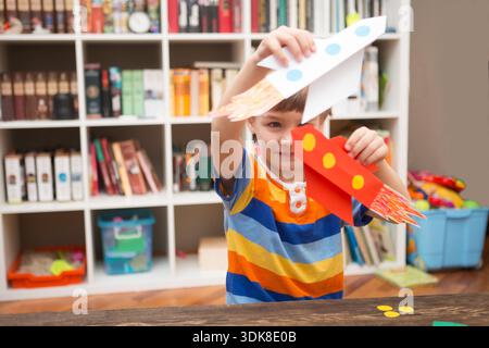 Vorschulkind in Kreativität im Haushalt. Glückliche Kinder machen Raketen aus Papier und spielen. Kreativität für Kinder. Kreative Kinder spielen mit Basteln. Internationaler Weltraumtag || Model veröffentlicht Stockfoto